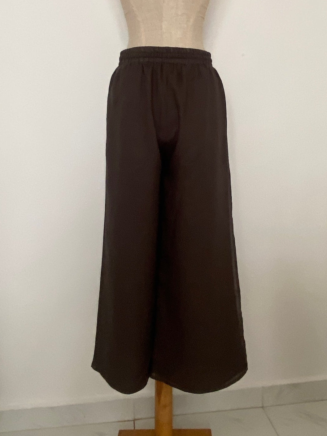 Dark brown wide-leg cropped pants displayed on a beige dress form mannequin against a plain white wall.